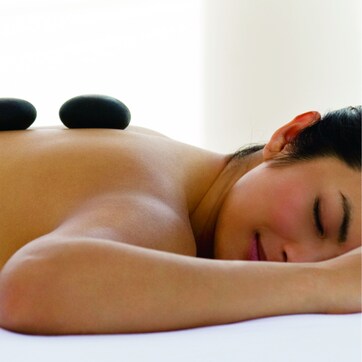 A person lying face down on a bed with their head resting on a pillow.