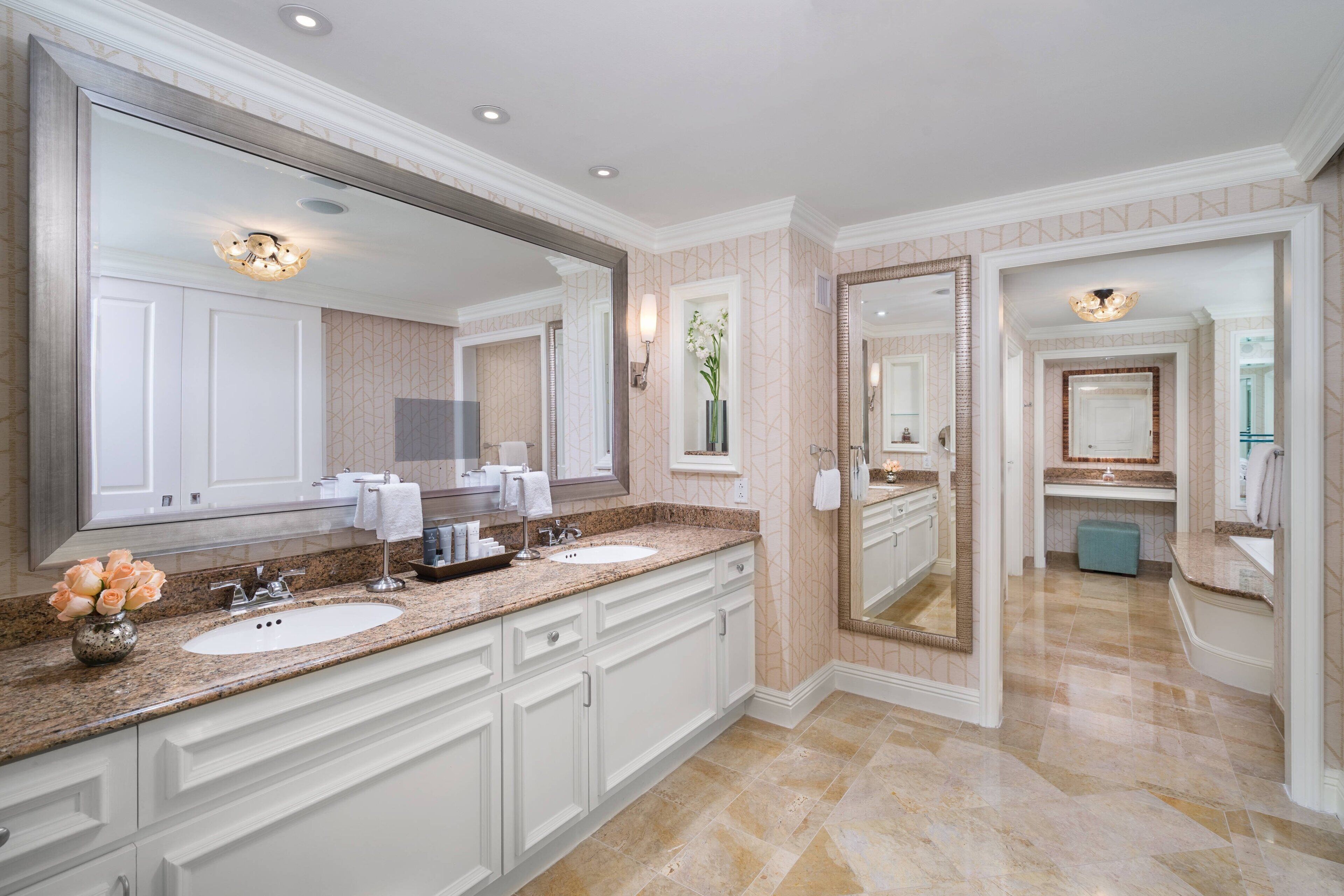 A spacious bathroom with two sinks, a large mirror, and a vanity area.