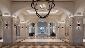 Un hall d’entrée spacieux, doté d’un sol à carreaux, de plafonds en arc de cercle et d’un lustre central.