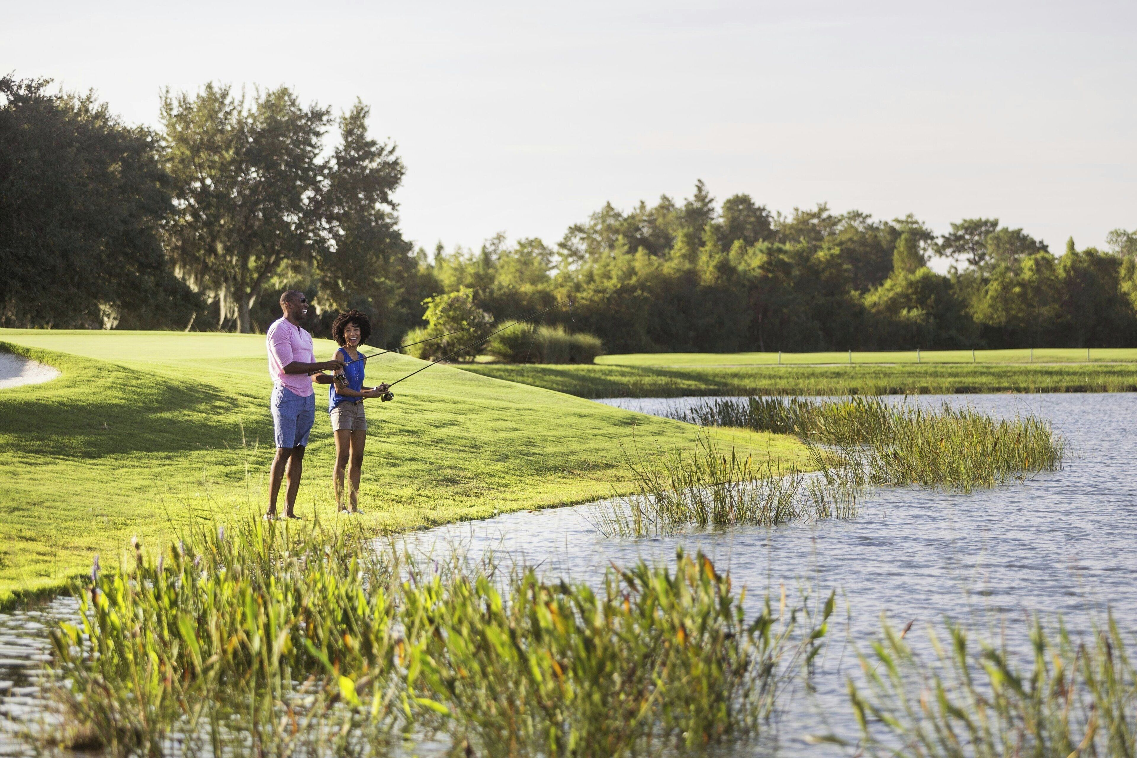 Ein Golfplatz mit einem Wasserhindernis und Bäumen im Hintergrund.