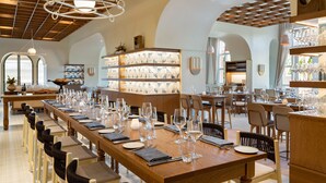 Un restaurant avec une longue table en bois dressée pour un repas, entourée de chaises.