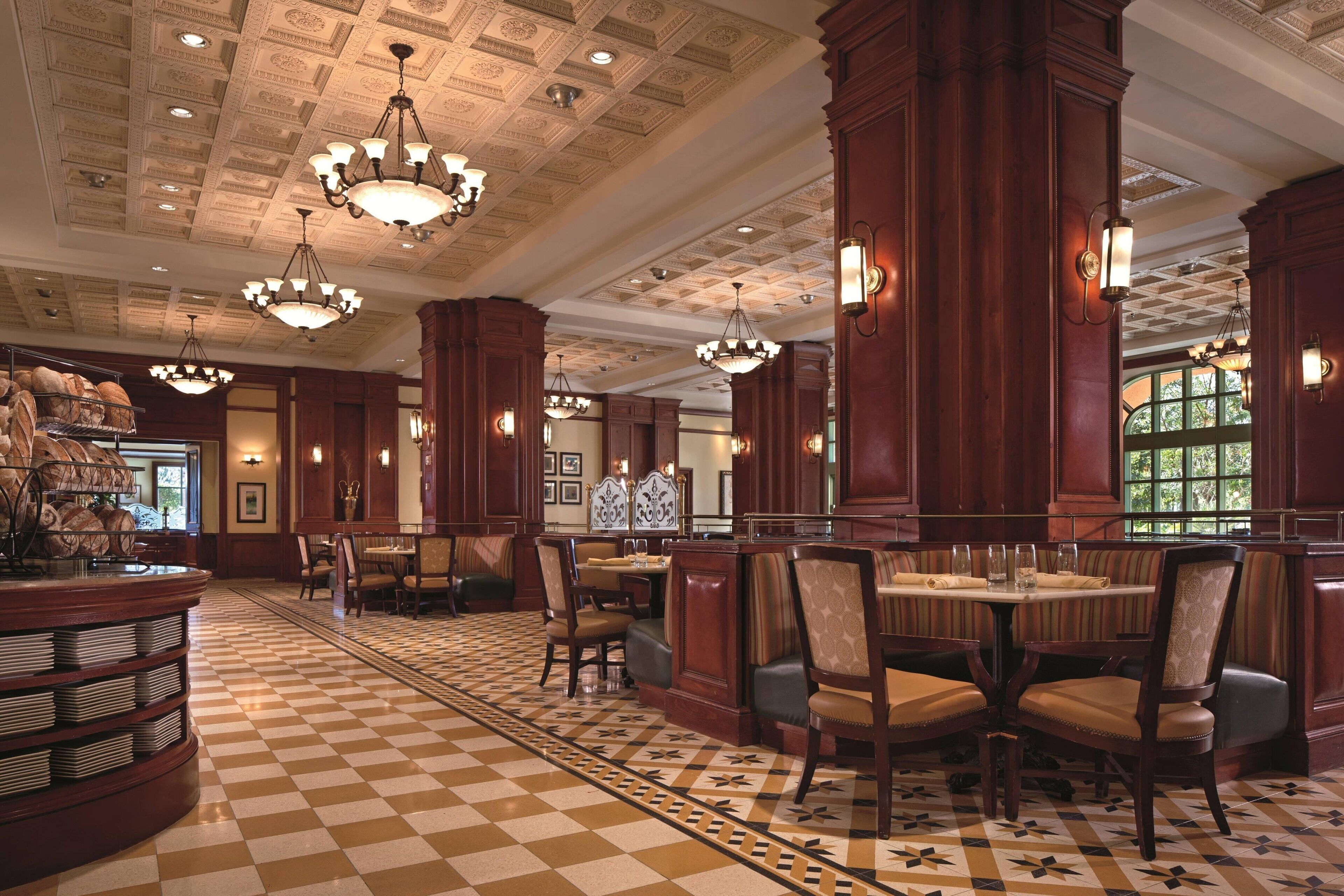 Un hall d’hôtel avec un sol à carreaux, des boiseries et des lustres.