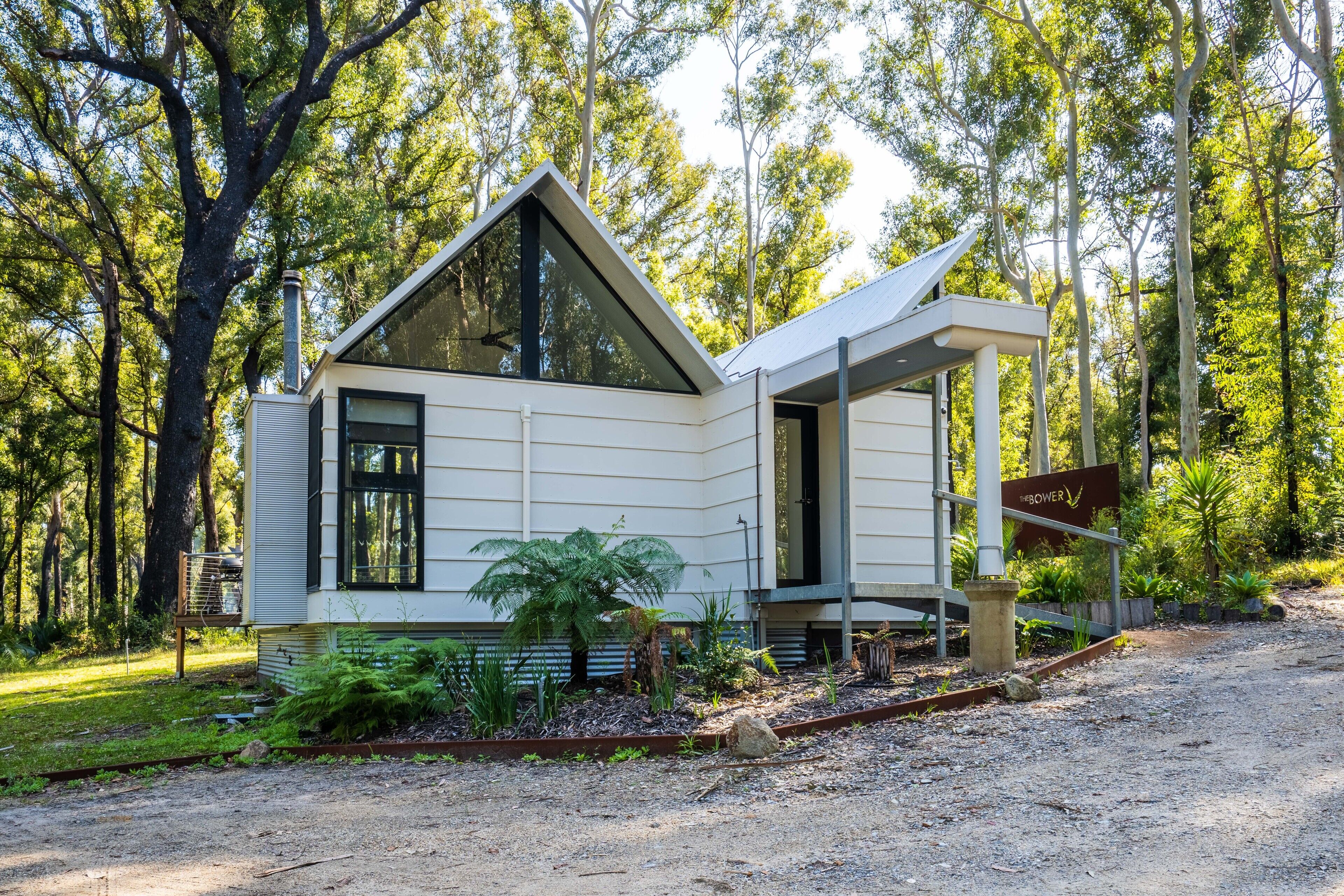Una cabaña moderna de un solo piso con techo inclinado, rodeada por un entorno forestal natural.