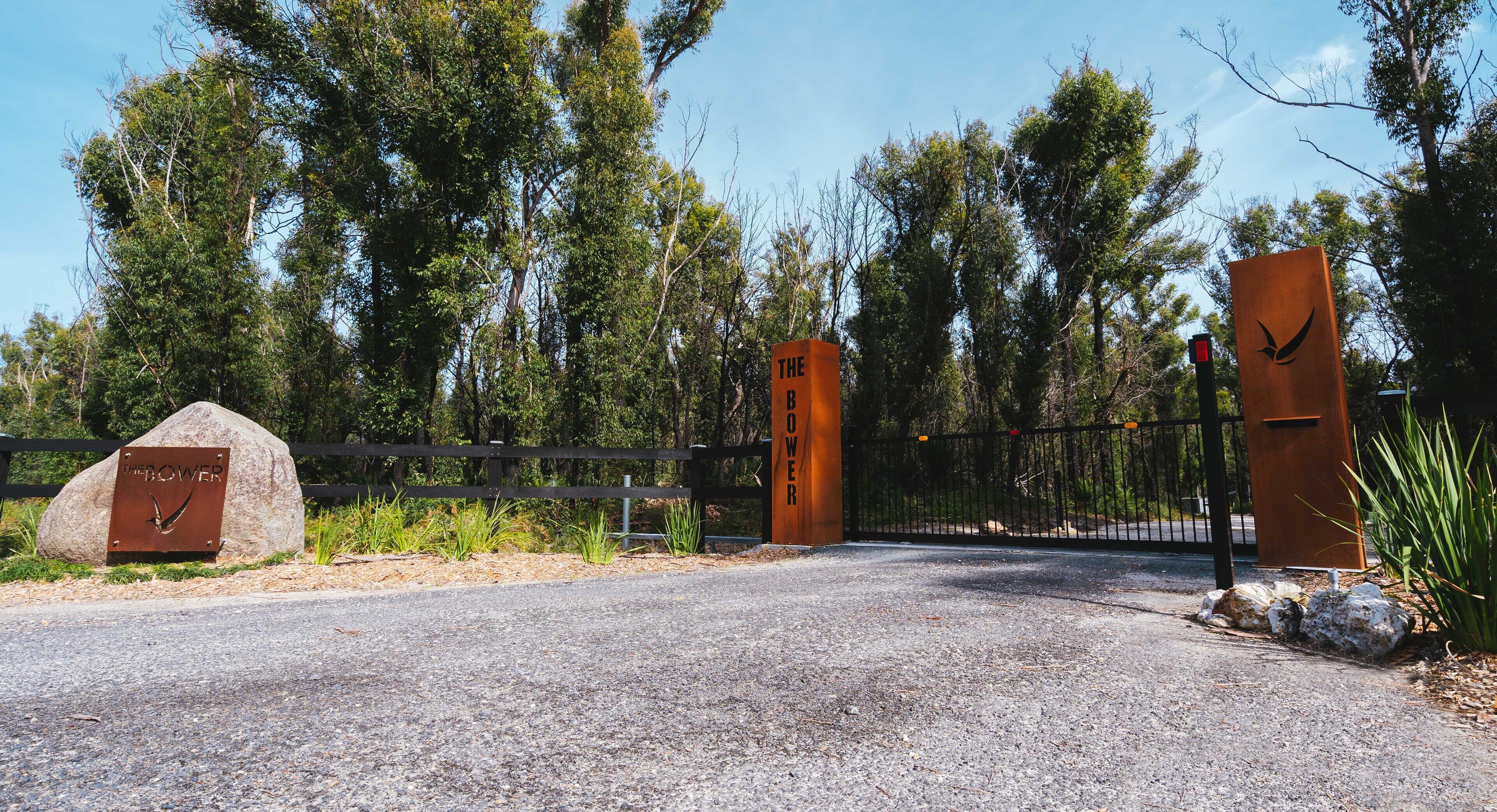 A gated entrance with a metal sign reading "THE BOWER" and a wooden sign with "THE BOWER" written on it.