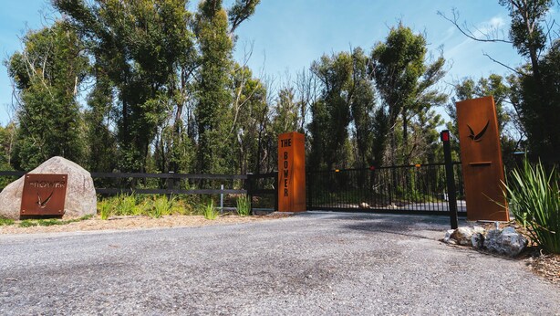 A gated entrance with a metal sign reading "THE BOWER" and a wooden sign with "THE BOWER" written on it.