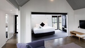 A modern bedroom with a large bed, a desk, and a TV. - The Bower at Broulee (Broulee)