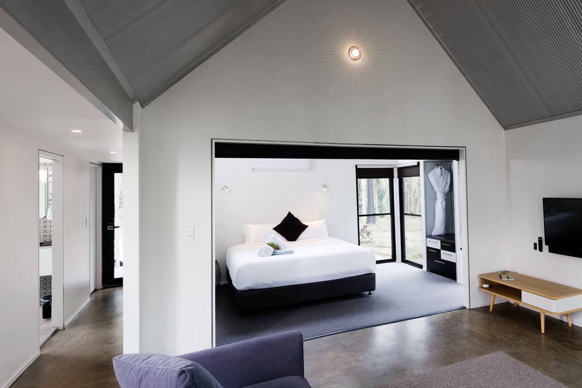 A modern bedroom with a large bed, a desk, and a TV.