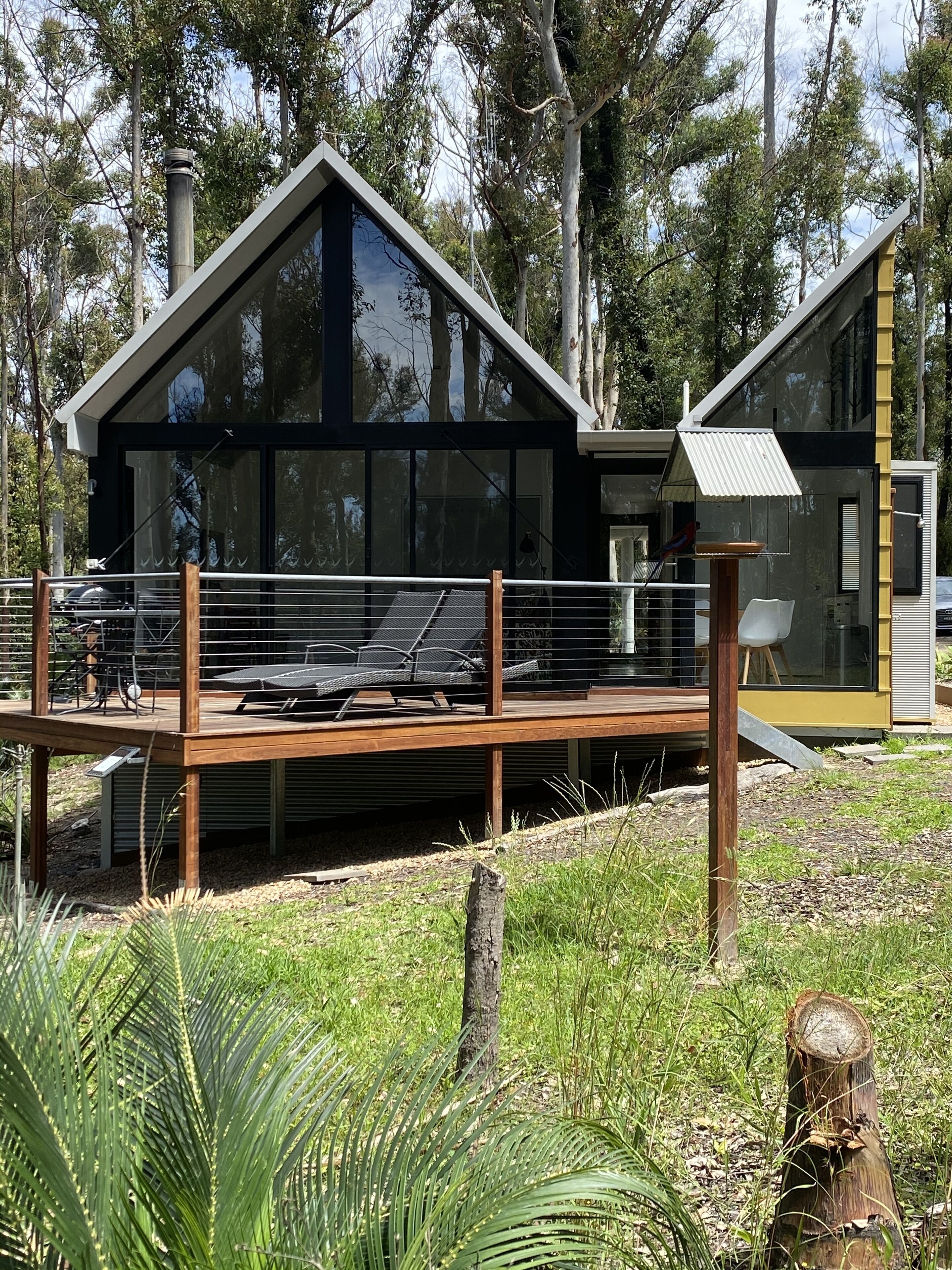 A modern house with a deck, large windows, and a bird feeder.