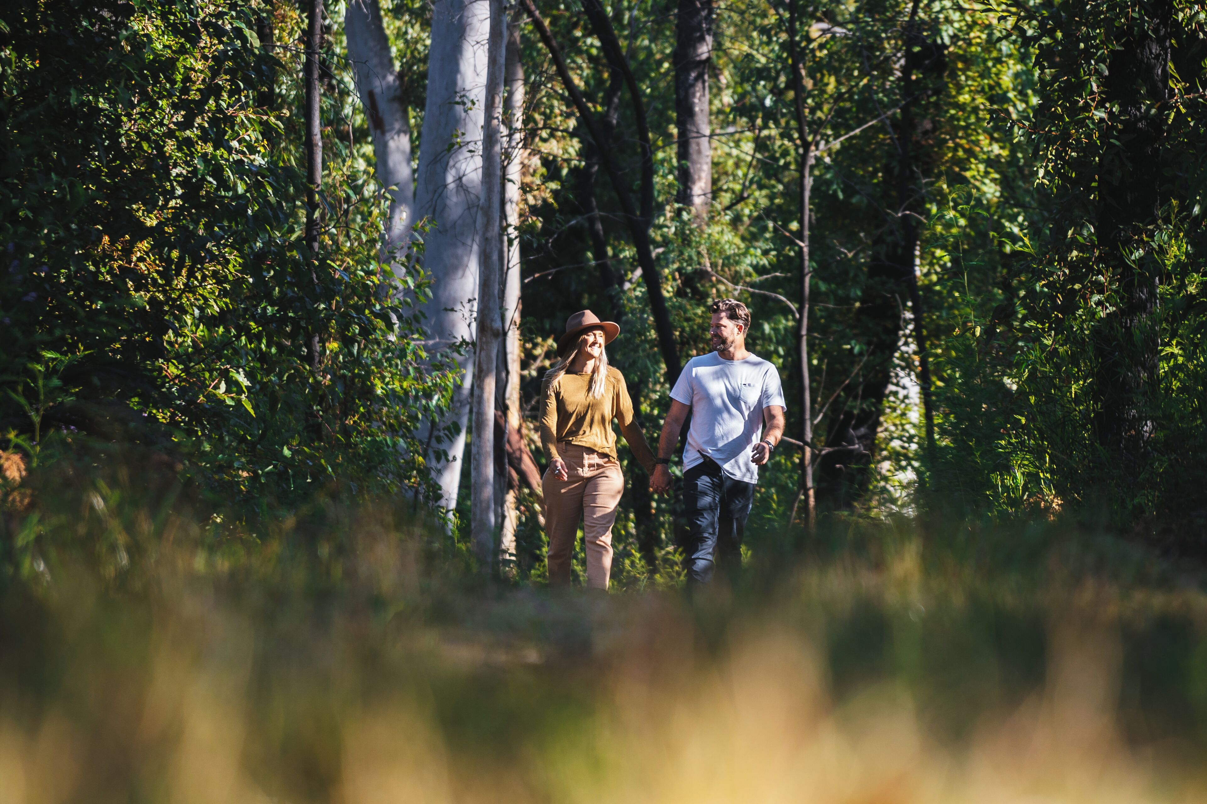 Two people walking through a forested area.