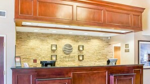 A reception desk with a stone wall backdrop, a logo, and a Dell computer. - Comfort Inn & Suites West Chester - North Cincinnati (West Chester)