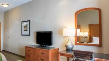 Une chambre d’hôtel comprenant un lit, un bureau avec une lampe, une chaise, une télévision et un miroir.