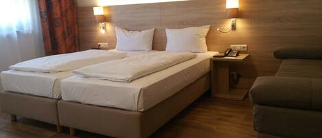 Una cama doble con dos almohadas, una mesita de noche con teléfono y un cabecero de madera.