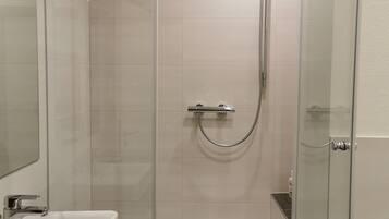 A modern bathroom with a glass-enclosed shower, a white sink, and a mirror.