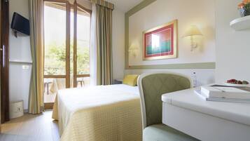 A hotel room with a bed, a desk, a chair, a TV, a painting, and a window with curtains.