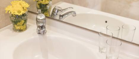A bathroom sink with a mirror, a faucet, and two clear glasses.
