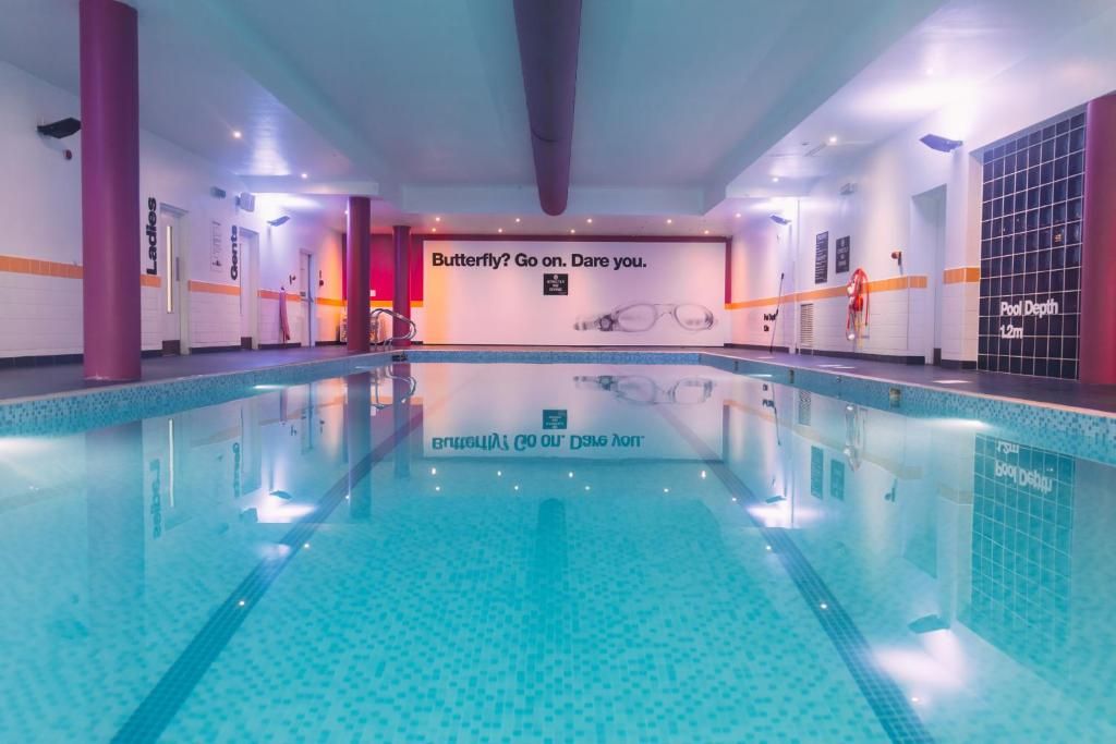 A swimming pool with a tiled floor and a sign that reads 'Butterfly? Go on. Dare you.'
