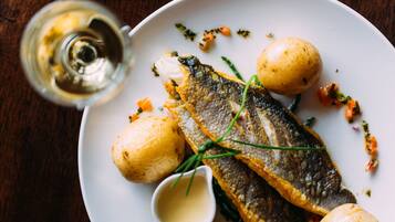 Un plato con pescado, patatas y un recipiente pequeño de salsa.