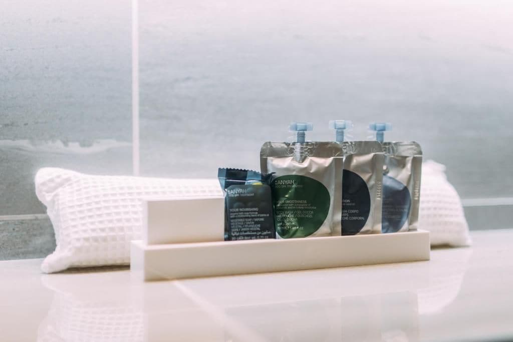 A bathroom with a white towel, a white bath mat, and a set of toiletries on a white tray.