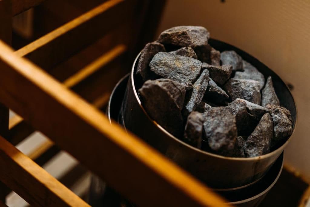 A metal bowl filled with rocks placed on a wooden chair.