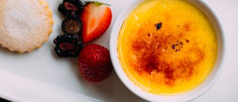 A dessert plate with crème brûlée, strawberries, and blackberries.