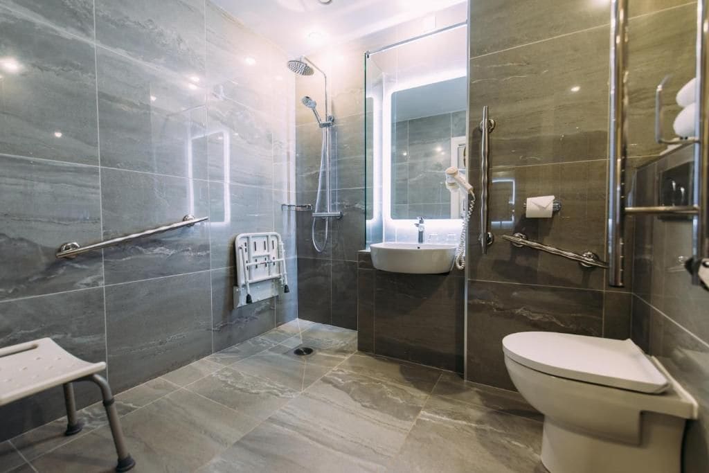 A modern bathroom with a glass-enclosed shower, a white sink, and a toilet.