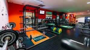 A gym with weightlifting equipment, a mirror, and a television on the wall. - Armagh City Hotel (Armagh)