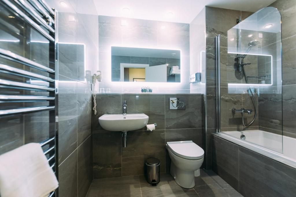 A modern bathroom with a glass-enclosed shower, a sink, and a toilet.