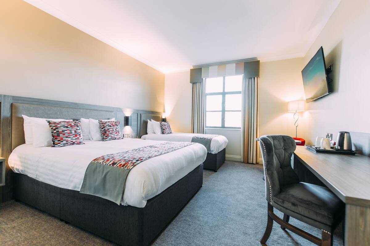 A hotel room with a large bed, two bedside tables, a desk, and a chair.
