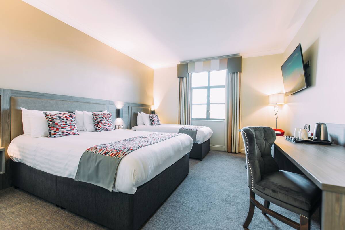 A hotel room with a large bed, two bedside tables, a desk, and a chair.