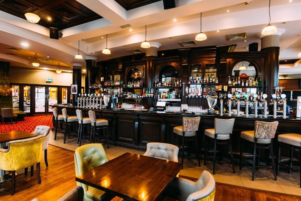 A bar area with multiple seating options, a bar counter, and a variety of bottles and glasses.