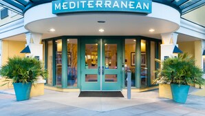 Entrada de hotel con un letrero que dice "Mediterranean" y una puerta de vidrio.
