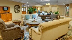 Un lobby amplio con techo alto, una mesa de recepción, asientos cómodos y un elemento decorativo en la pared.