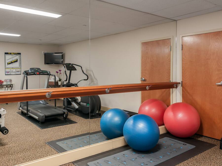 A gym with exercise equipment, a treadmill, and exercise balls.