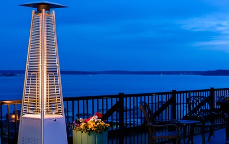 A tall, white heater with a metal grill, a wooden fence, and a view of the water.