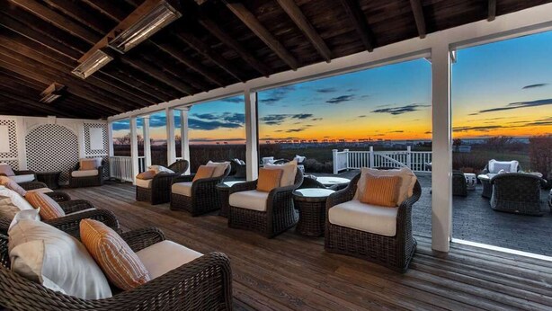 An outdoor seating area with wicker furniture and a view of the sunset. - The Wauwinet (Nantucket)