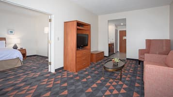 A hotel room with a bed, a TV, a sofa, a coffee table, and a dresser.