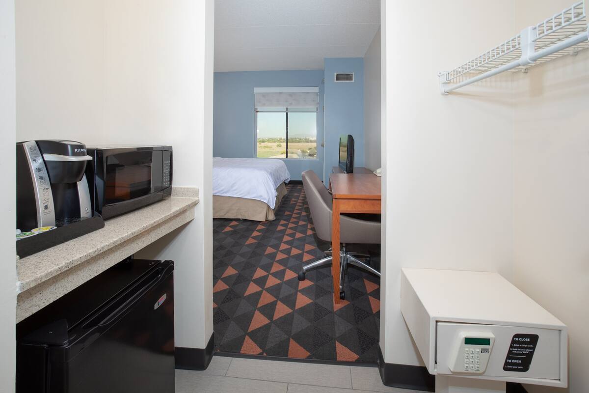 Habitación de hotel con cama, escritorio, microondas, refrigerador y ventana con vistas.