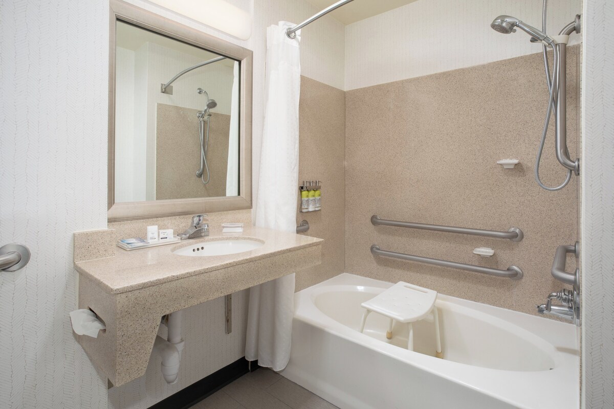 A modern bathroom with a bathtub, a shower, a vanity with a sink, and a mirror.