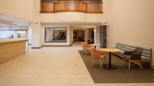 A spacious lobby with a reception desk, seating area, and a staircase to an upper level. - Holiday Inn & Suites Goodyear - West Phoenix Area by IHG (Goodyear)