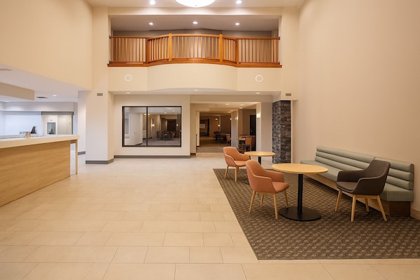A spacious lobby with a reception desk, seating area, and a staircase to an upper level. - Holiday Inn & Suites Goodyear - West Phoenix Area by IHG (Goodyear)