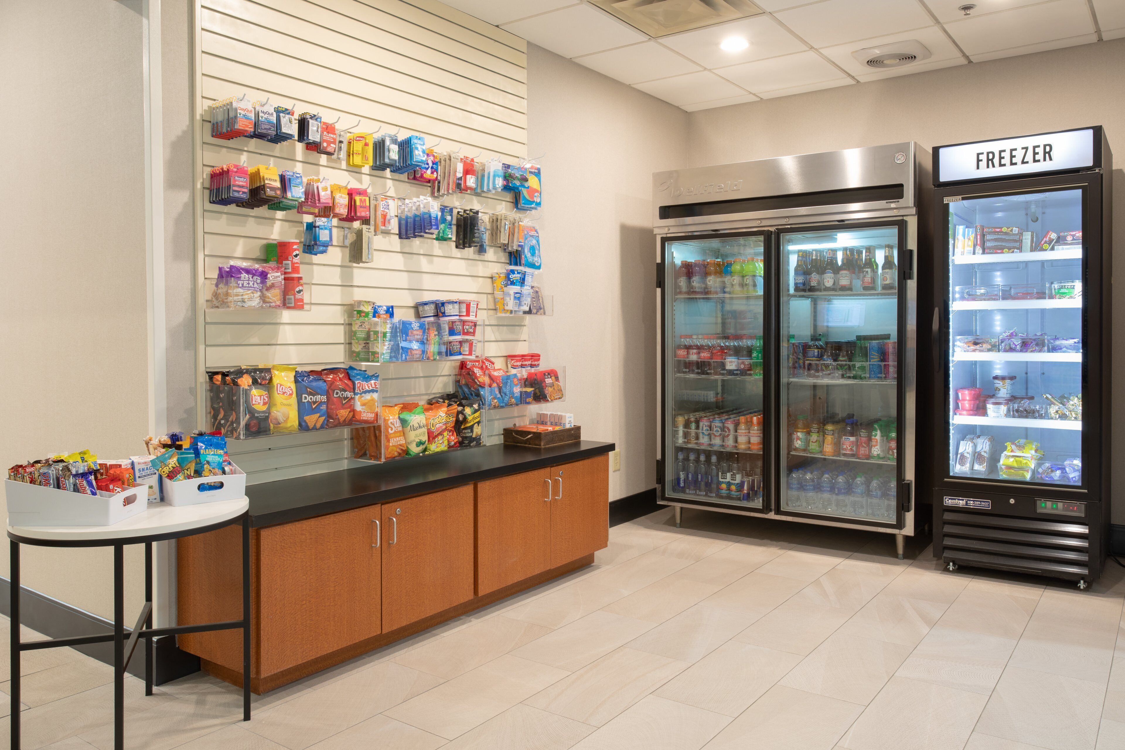 Un espace de restauration en libre-service proposant une variété de collations et de boissons emballées, un rayon de produits surgelés et un sol carrelé propre.