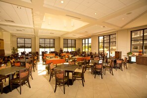 A spacious dining area with multiple tables and chairs, large windows, and a clean, modern interior. - Ramada Plaza Resort & Suites by Wyndham Orlando Intl Drive (Orlando)