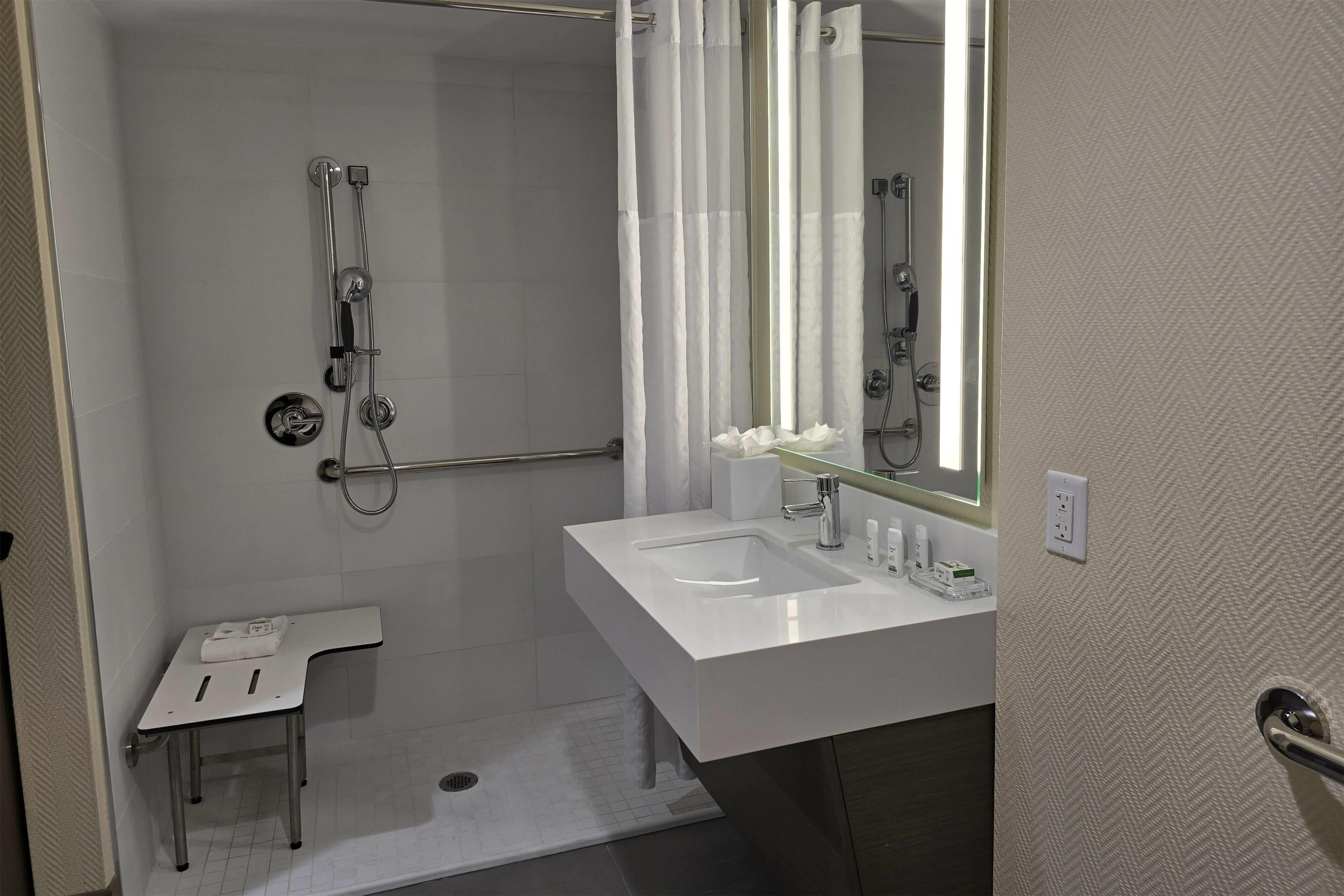 A bathroom with a shower, a sink, a mirror, and a towel rack.