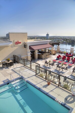 A rooftop pool area with Skybar seating, a bar, and a view of the city skyline. - Ramada Plaza Resort & Suites by Wyndham Orlando Intl Drive (Orlando)