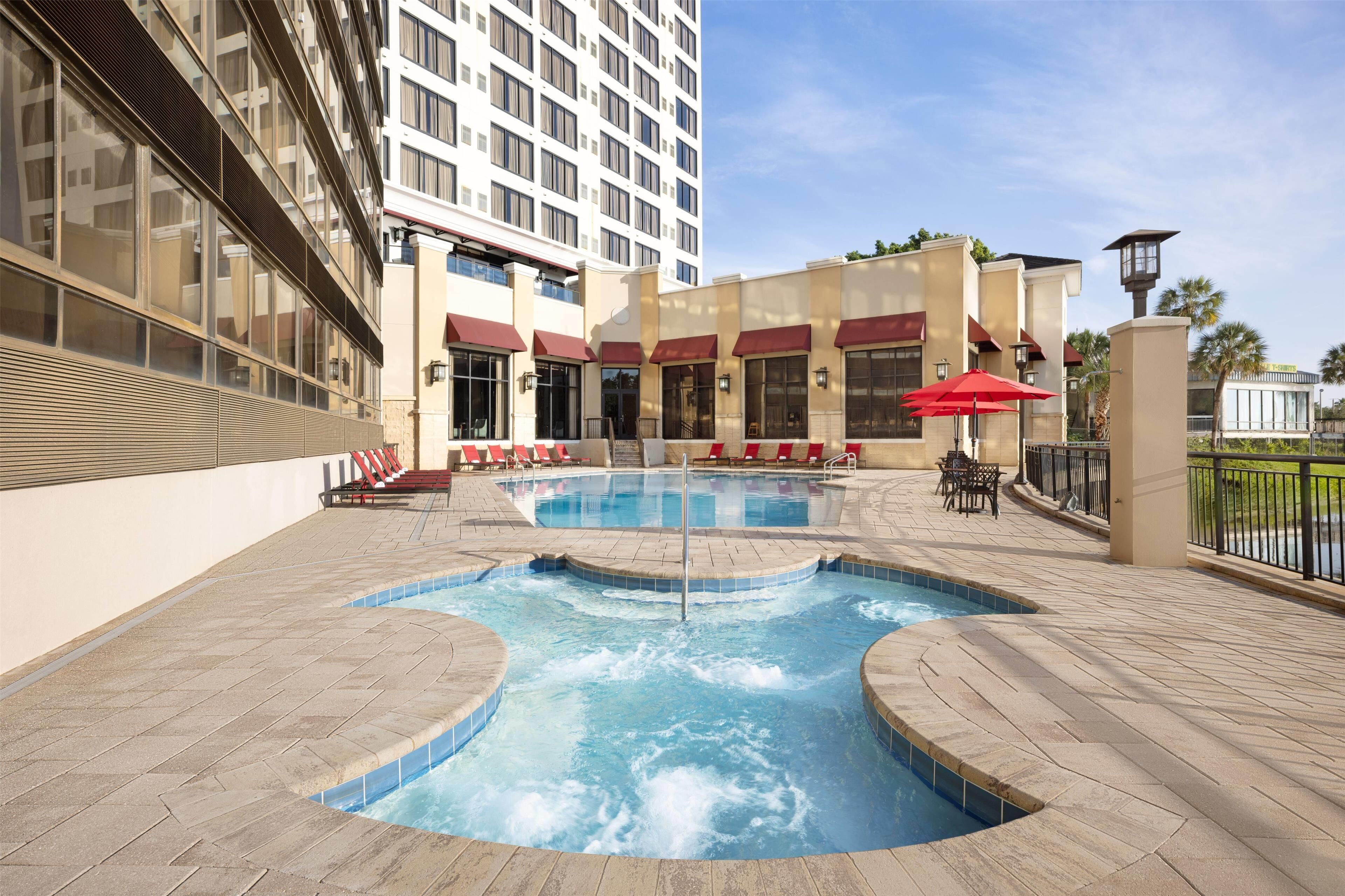A hotel with a pool area, outdoor seating, and a building with multiple windows and balconies.