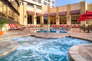 Ein Hotelpoolbereich mit mehreren Liegestühlen und einem Whirlpool.