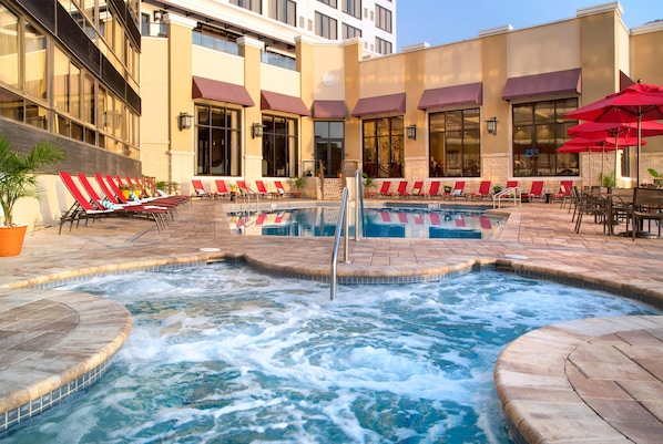 A hotel pool area with multiple lounge chairs and a hot tub. - Ramada Plaza Resort & Suites by Wyndham Orlando Intl Drive (Orlando)