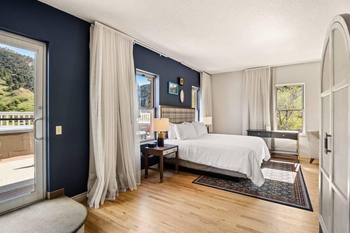 Un dormitorio con una cama, un escritorio, una silla, una ventana y vistas a un balcón.