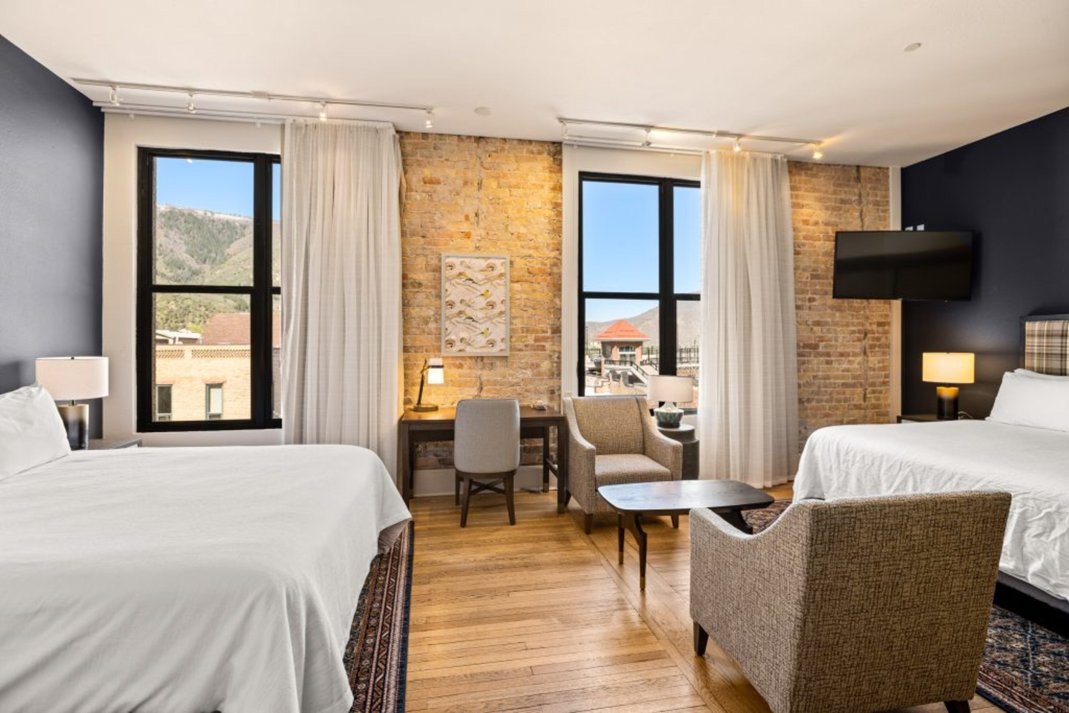 Ein Hotelzimmer mit zwei Betten, einem Schreibtisch, einem Stuhl und einem Fernseher.
