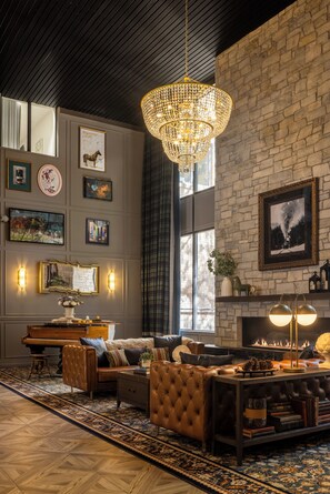 A cozy living room with a fireplace, a chandelier, and a large window. - Hotel Maxwell Anderson (Glenwood Springs)